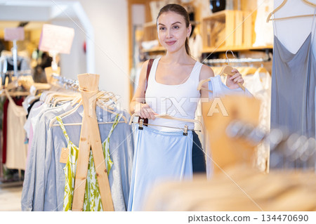 Young woman choosing skirt and blouse in clothing store 134470690