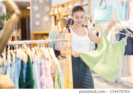 Young woman choosing tank top Young woman choosing tank top 134470703