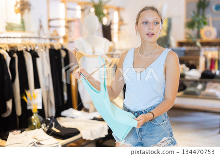 Girl customer chooses singlet blouse in branded store Girl customer chooses singlet blouse in branded store 134470753