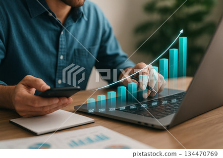 AI generated digital business growth with a man reviewing rising holographic bar charts using a laptop and smartphone in a warm modern workspace AI generated digital business growth with a man reviewing rising holographic bar charts using a laptop and smartphone in a warm modern workspace 134470769