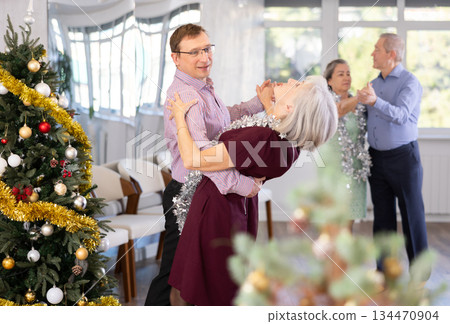 Middle-aged man and elderly woman dancing contemporary discofox in couple in New Year atmosphere 134470904
