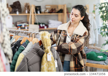Young woman chooses outerwear in store Young woman chooses outerwear in store 134471056