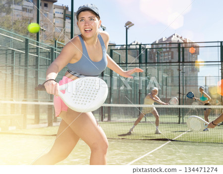 Young motivated woman playing padel with her teammate in court 134471274