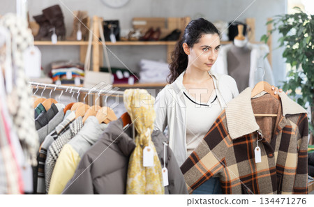 Armenian woman near showcase examine goods, buying checkered jacket Armenian woman near showcase examine goods, buying checkered jacket 134471276