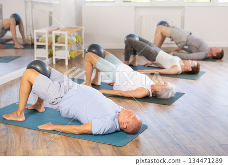 Elderly man doing pilates with softball Elderly man doing pilates with softball 134471289
