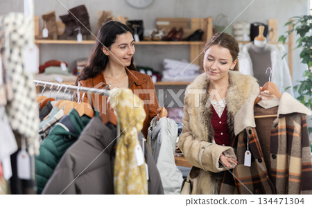 Two women standing in a store and choosing clothes for autumn and winter Two women standing in a store and choosing clothes for autumn and winter 134471304