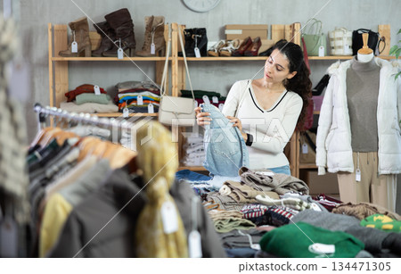 Female shopper chooses a jeans trousers in clothing store Female shopper chooses a jeans trousers in clothing store 134471305