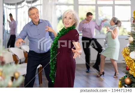Senior man and elderly woman are dancing contemporary twist in couple in New Year studio atmosphere Senior man and elderly woman are dancing contemporary twist in couple in New Year studio atmosphere 134471340