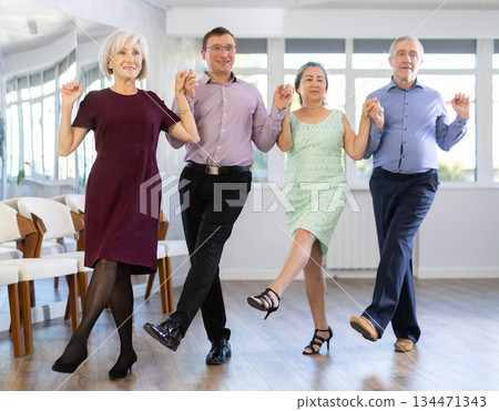Group of elderly people with middle-aged man perform Irish folk dance 134471343