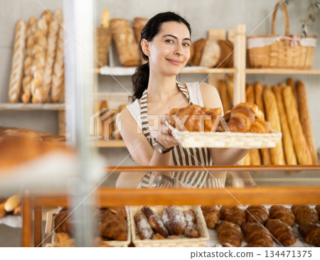 Young woman seller with basket of croissants 134471375