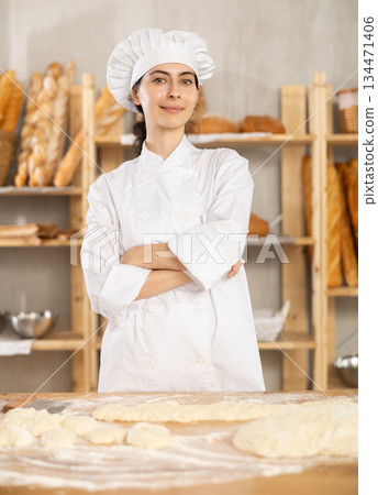 Young female baker at table with dough Young female baker at table with dough 134471406