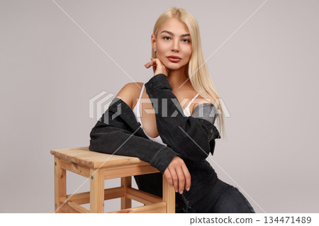 Model poses gracefully on a stool, lost in thought Model poses gracefully on a stool, lost in thought 134471489