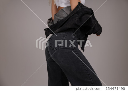 Model poses in black denim jeans and layered outerwear 134471490