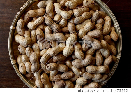 A pile of shelled peanuts in a bamboo basket with a table in the background, viewed from directly above A pile of shelled peanuts in a bamboo basket with a table in the background, viewed from directly above 134473362
