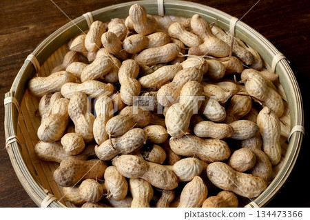 A lot of shelled peanuts in a bamboo colander on a table background A lot of shelled peanuts in a bamboo colander on a table background 134473366