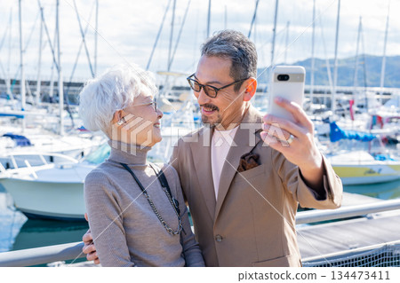 Senior couple taking a selfie at the harbor. Photo courtesy of Ito Marine Town Roadside Station. Senior couple taking a selfie at the harbor. Photo courtesy of Ito Marine Town Roadside Station. 134473411