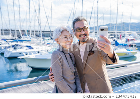 Senior couple taking a selfie at the harbor. Photo courtesy of Ito Marine Town Roadside Station. 134473412