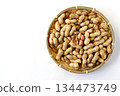A large number of shelled peanuts in a bamboo basket on a white background, viewed from directly above 134473749