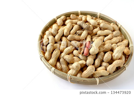 A lot of shelled peanuts in a bamboo basket on a white background A lot of shelled peanuts in a bamboo basket on a white background 134473920