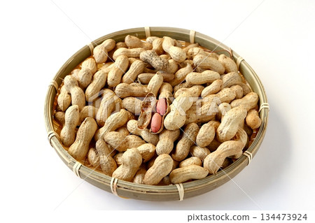 A lot of shelled peanuts in a bamboo basket on a white background A lot of shelled peanuts in a bamboo basket on a white background 134473924