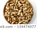A large number of shelled peanuts in a bamboo basket on a white background, viewed from directly above 134474077