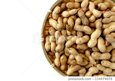 A large number of shelled peanuts in a bamboo basket on a white background, viewed from directly above A large number of shelled peanuts in a bamboo basket on a white background, viewed from directly above 134474078