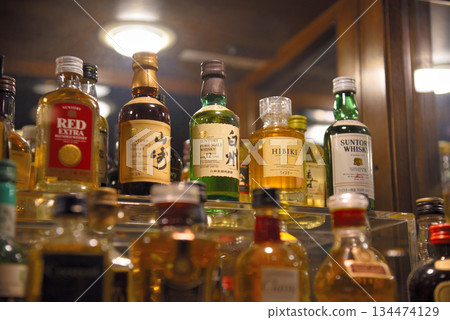 Image of miniature bottles of whiskey lined up on a shelf 134474129