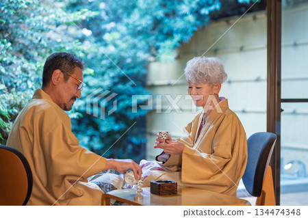 A senior couple drinking sake on the veranda of a traditional Japanese inn. Photo courtesy of Ito Ryokuyo. A senior couple drinking sake on the veranda of a traditional Japanese inn. Photo courtesy of Ito Ryokuyo. 134474348
