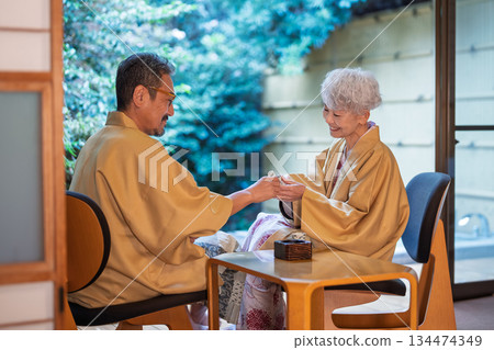 A senior couple drinking sake on the veranda of a traditional Japanese inn. Photo courtesy of Ito Ryokuyo. 134474349