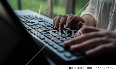 Close-up of Hands Typing on a Computer Keyboard with Digital Financial Charts Blurred in the Background for Business and Technology Concept Scalp 134474679