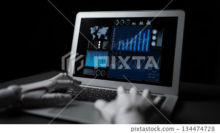 Futuristic robotic hand interacting with laptop screen displaying data graphs, charts, and world map analysis in a modern tech environment Scalp 134474728