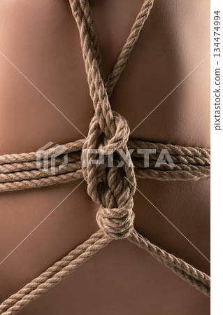 Rope tied in a detailed knot around a person's back showing a specific tying technique at a workshop session Rope tied in a detailed knot around a person's back showing a specific tying technique at a workshop session 134474994