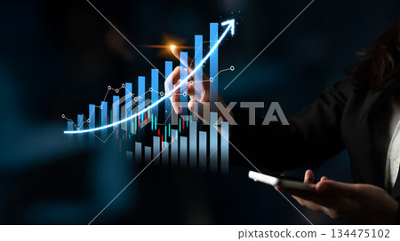 Business Professional Analyzing Financial Growth Data with Smartphone in Dark Office with Graphs and Charts on Digital Screen for Economic Success Scalp 134475102