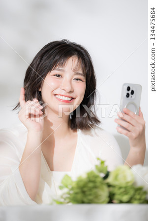 一位快樂、容光煥發的年輕女子正近距離看著她的智慧型手機,搜尋、點擊、看著相機。 一位快樂、容光煥發的年輕女子正近距離看著她的智慧型手機,搜尋、點擊、看著相機。 134475684