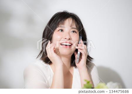 特寫鏡頭展現了一位快樂開朗的年輕女子正在使用智慧型手機通話。她臉上露出詢問、連結、回憶和構思等表情。 特寫鏡頭展現了一位快樂開朗的年輕女子正在使用智慧型手機通話。她臉上露出詢問、連結、回憶和構思等表情。 134475686