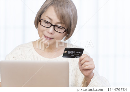 Senior woman enjoying online shopping on a computer Senior woman enjoying online shopping on a computer 134476784
