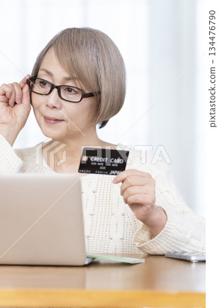 在電腦上享受網上購物的高級女性 在電腦上享受網上購物的高級女性 134476790