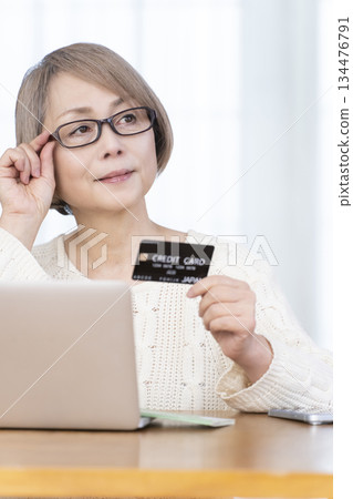 Senior woman enjoying online shopping on a computer Senior woman enjoying online shopping on a computer 134476791