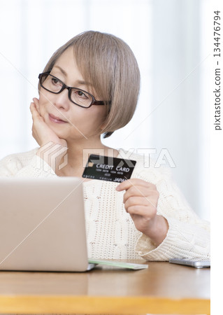 Senior woman enjoying online shopping on a computer Senior woman enjoying online shopping on a computer 134476794