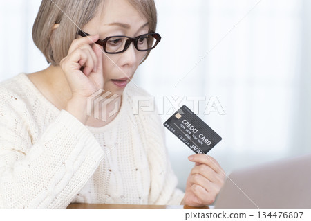 在電腦上享受網上購物的高級女性 在電腦上享受網上購物的高級女性 134476807