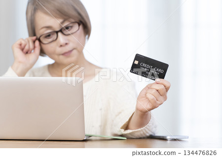 Senior woman enjoying online shopping on a computer, out of focus Senior woman enjoying online shopping on a computer, out of focus 134476826