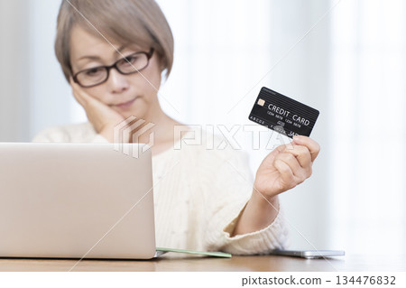 一位老年婦女正在電腦上進行線上購物,畫面模糊不清。 一位老年婦女正在電腦上進行線上購物,畫面模糊不清。 134476832