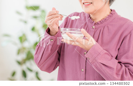 A gray-haired senior woman who eats yogurt and dairy products (bifidobacteria, lactic acid bacteria, dairy products, intestinal health) 134480302