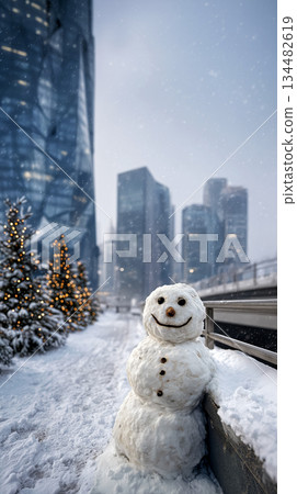 A snowman stands on a snow-covered sidewalk against a backdrop of a business center. It's snowing heavily on Christmas Eve. Vertical poster 134482619