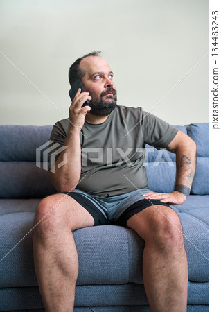 Man talks on phone while sitting at home Man talks on phone while sitting at home 134483243