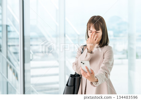 Asian businesswoman who has difficulty seeing the screen of her smartphone due to presbyopia, blurred vision, and eye strain 134483596