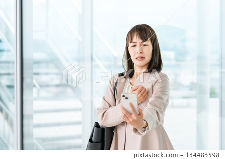 Asian businesswoman who has difficulty seeing the screen of her smartphone due to presbyopia, blurred vision, and eye strain Asian businesswoman who has difficulty seeing the screen of her smartphone due to presbyopia, blurred vision, and eye strain 134483598