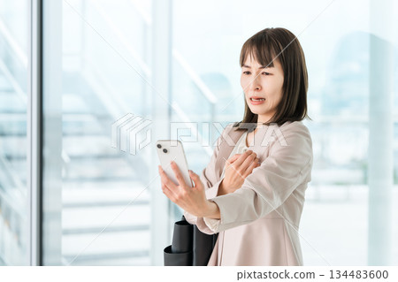 Asian businesswoman who has difficulty seeing the screen of her smartphone due to presbyopia, blurred vision, and eye strain 134483600