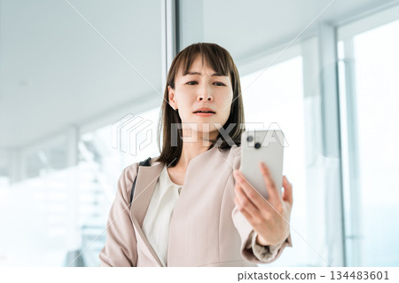 一位亞洲女商人因老花眼、視力模糊和眼睛疲勞而難以看清智慧型手機螢幕。 134483601
