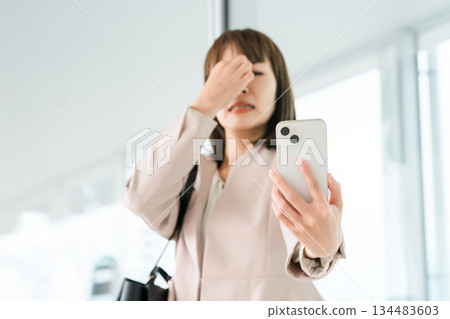 一位亞洲女商人因老花眼、視力模糊和眼睛疲勞而難以看清智慧型手機螢幕。 一位亞洲女商人因老花眼、視力模糊和眼睛疲勞而難以看清智慧型手機螢幕。 134483603